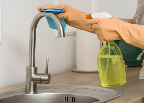 Main nettoyant un robinet mitigeur avec produit non abrasif